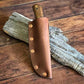 Patch knife with black walnut handle, SEEK Outdoors blade holstered and sitting against a log